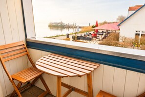 A wooden chair and table on a balcony with a view of a river and outdoor seating area.