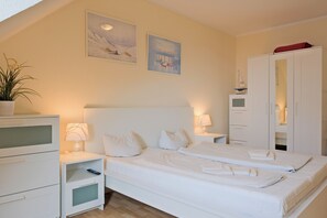 Une chambre à coucher comprenant un lit, des tables de chevet, une armoire et deux tableaux accrochés au mur.