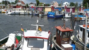 Un puerto deportivo con varias embarcaciones amarradas, rodeado de edificios y un cielo nublado.