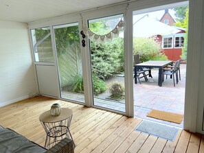 Ein Zimmer mit einer Schiebetür zu einer Terrasse im Freien, ausgestattet mit Tisch und Stühlen.