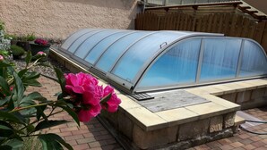 A greenhouse structure with a curved glass roof, a stone base, and a metal vent.