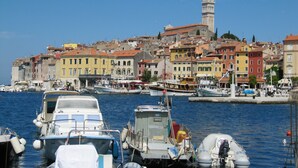 Un porto con imbarcazioni ormeggiate, edifici colorati e una torre imponente sullo sfondo.