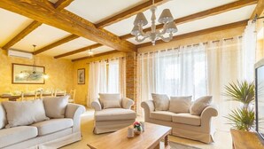 Een ruime woonkamer met houten plafond, twee banken, een salontafel en een televisie.