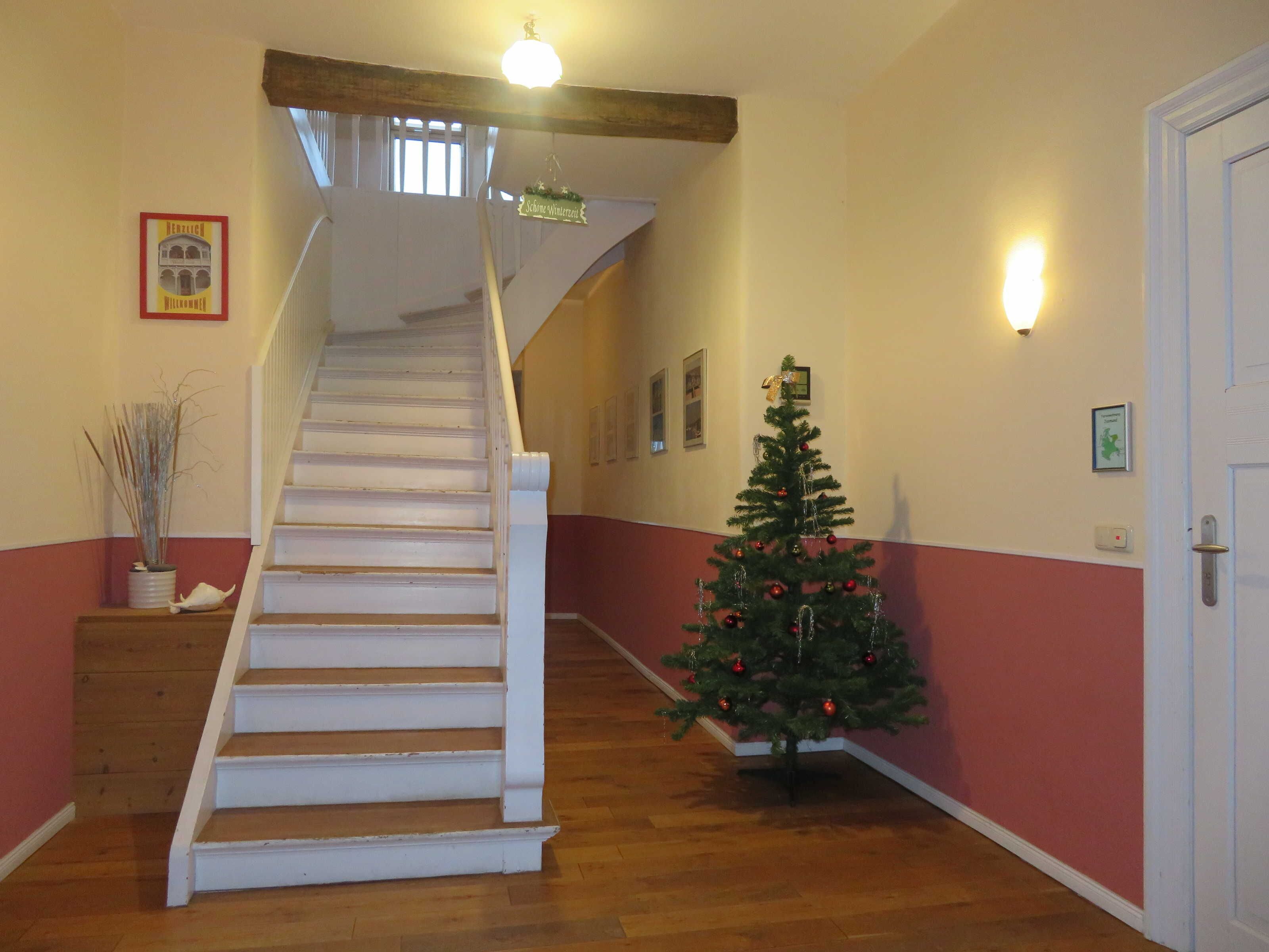 A staircase with a Christmas tree and wall-mounted lights.