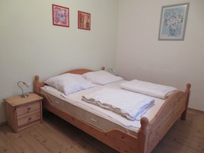 A single-bed room with a wooden headboard, a nightstand with drawers, and a bedside table with a lamp. There are two framed pictures on the wall. - Jasmund - Pension Waldrose (Sellin)