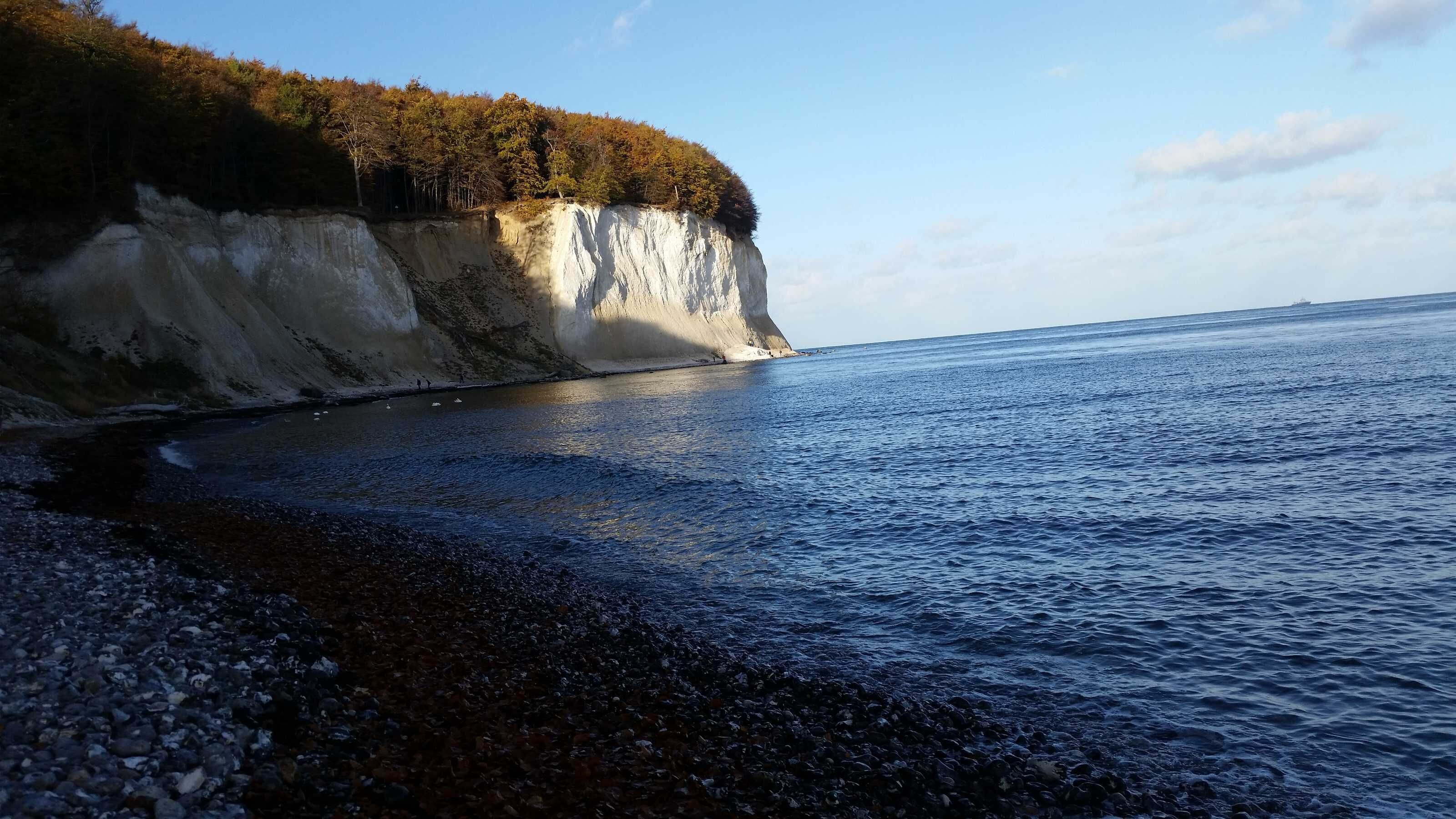 Eine Küstenlandschaft mit felsigem Ufer, einer Klippe und ruhiger See.