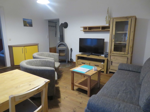 Un salon comprenant un canapé, des fauteuils, un téléviseur, une cheminée et des meubles en bois.