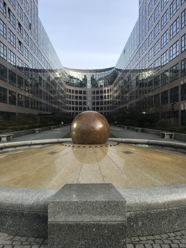 Een modern gebouw met een centrale binnenplaats en een grote, bolvormige sculptuur.