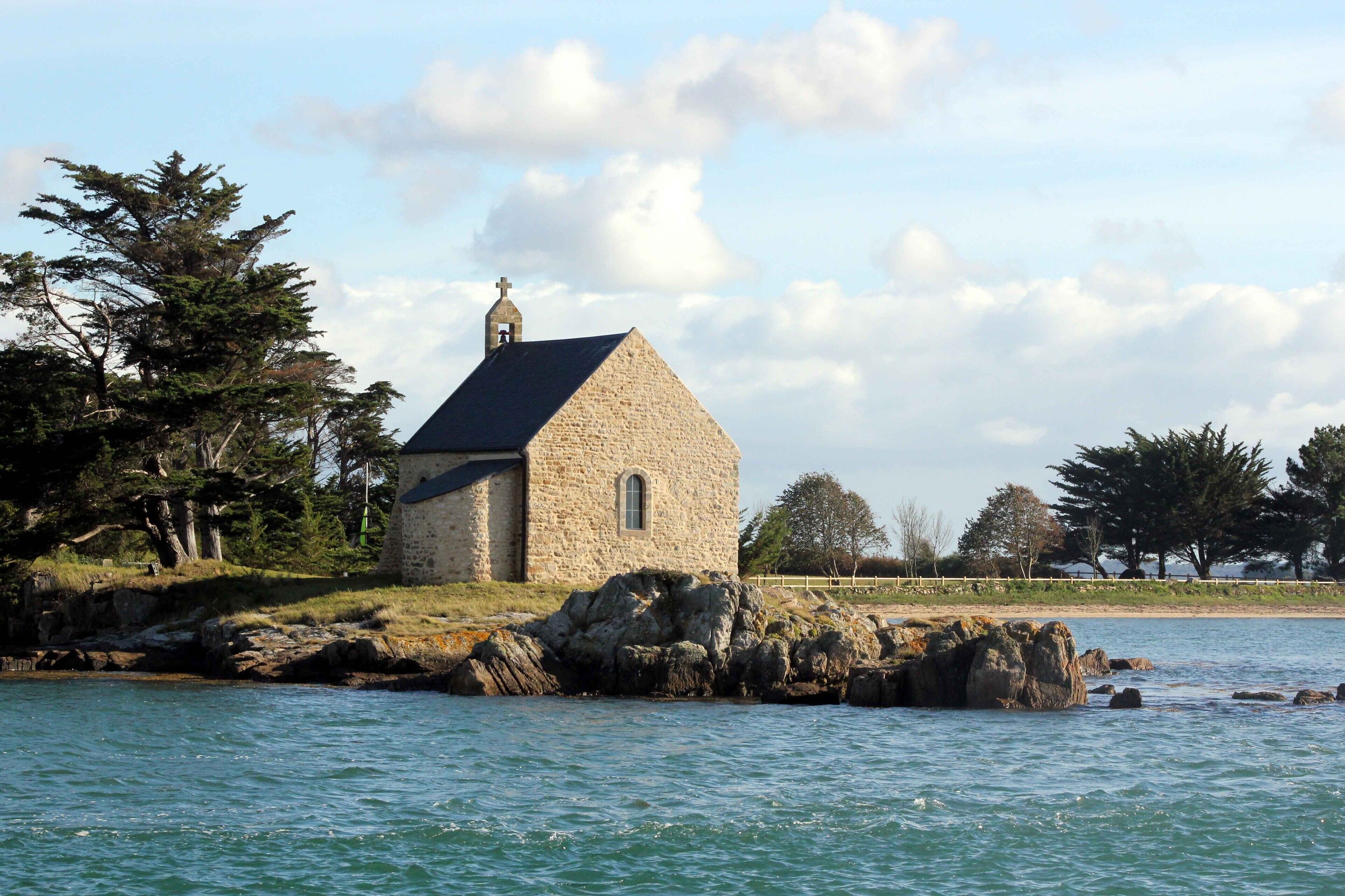Une église en pierre dotée d’un clocher, située sur une côte rocheuse.