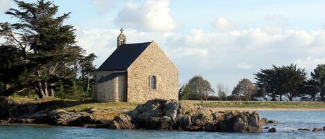Une église en pierre dotée d’un clocher, située sur une côte rocheuse.
