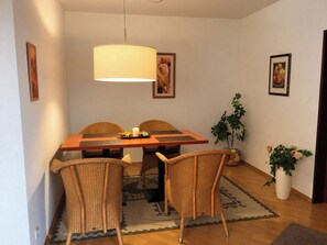 A dining area with a table, chairs, a hanging light fixture, and wall-mounted artwork.