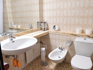 A bathroom with a sink, bidet, toilet, and a mirror.