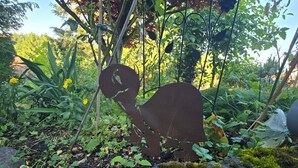 Ein Garten mit einer Metall-Schildkröten-Skulptur, umgeben von viel Grün und Pflanzen.