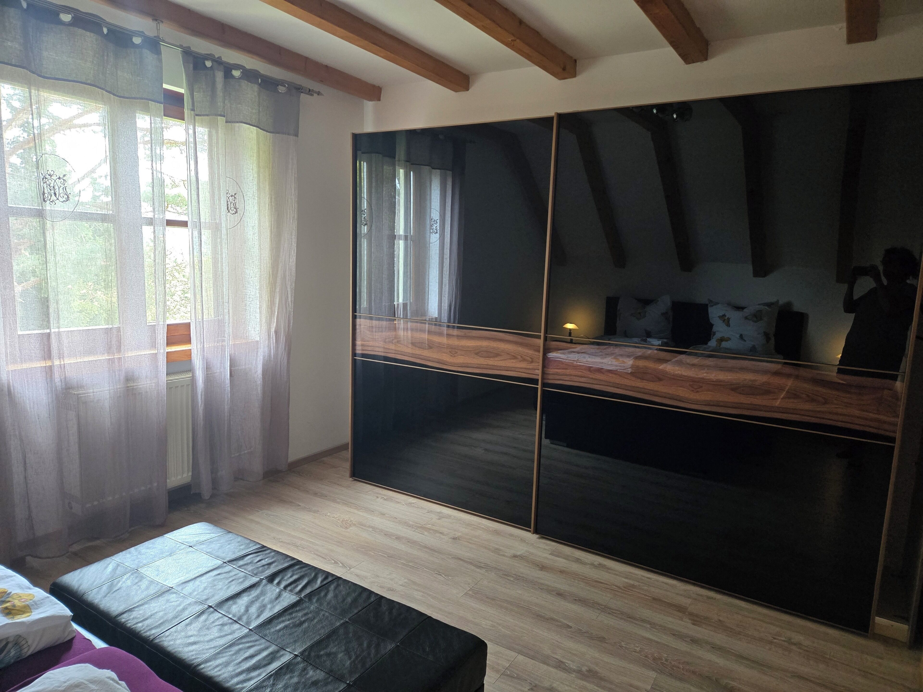 Ein Schlafzimmer mit einem großen Spiegel, Holzboden und einem Bett mit einer schwarzen Matratze.