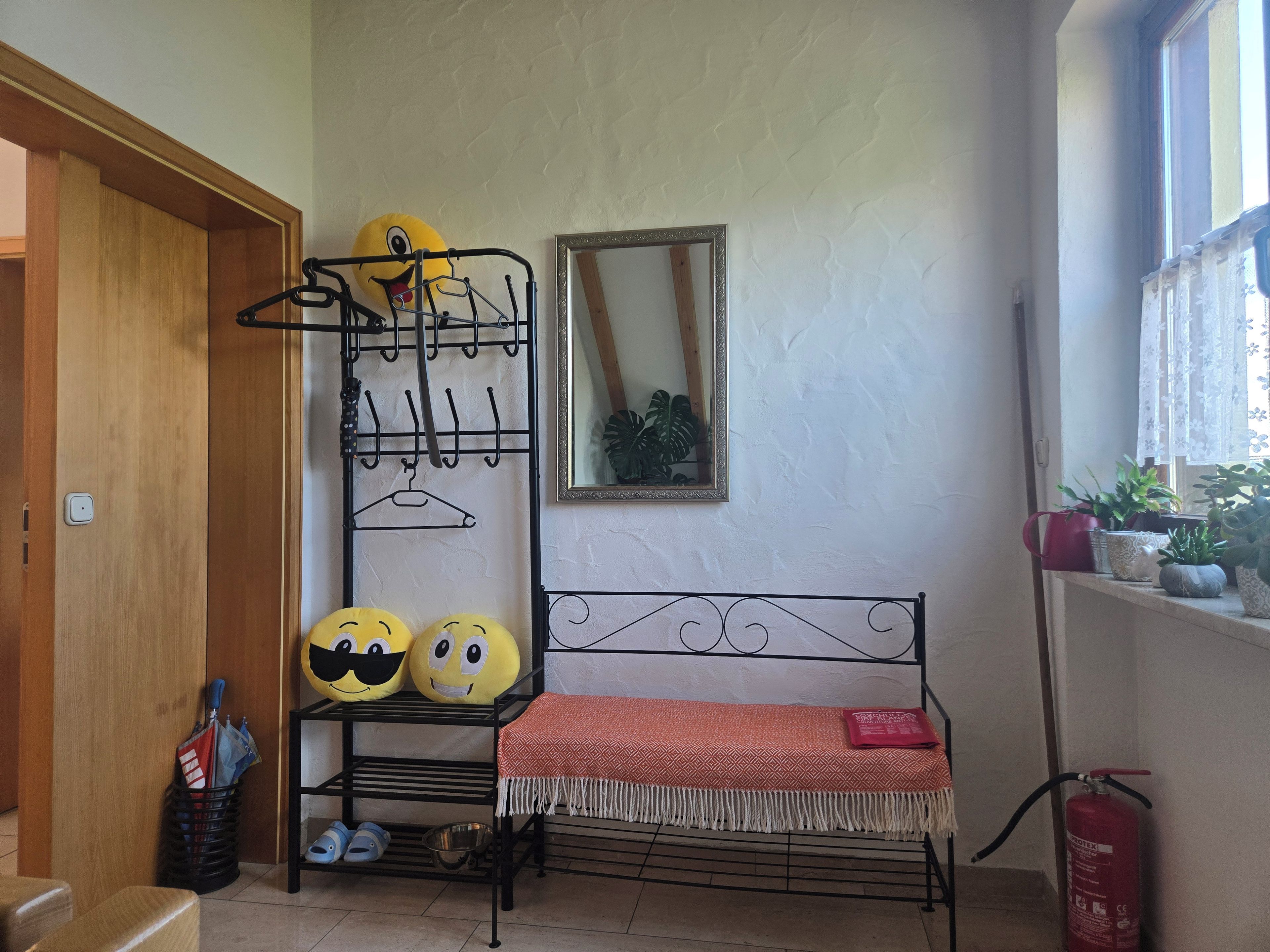 Una habitació amb un llit superposat, un penjador fixat a la paret, un mirall i un extintor.