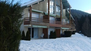 A modern multi-story building with a balcony, surrounded by snow and trees. - Charming apartment in chalet, close to ski slopes and town center    (Gérardmer)