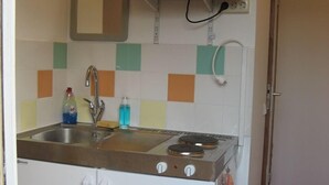Cocina compacta con microondas, fregadero y estufa.