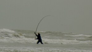 Una persona pescando en mar agitado.