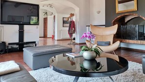 A modern living room with a flat-screen TV, leather sofa, and a round glass coffee table.