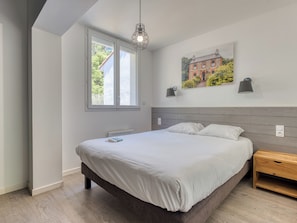Una camera da letto con un letto, una finestra, una lampada a parete e un quadro.