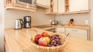 Cozinha equipada com micro-ondas, cafeteira e uma cesta de frutas no balcão.