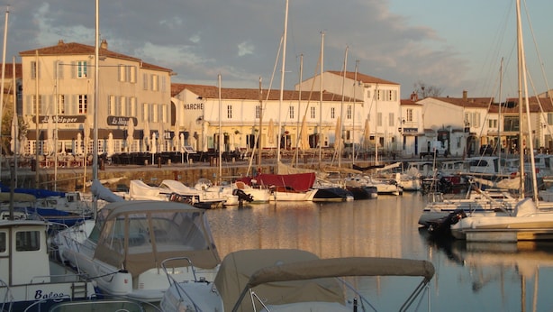 Un puerto deportivo con barcos amarrados, un hotel llamado "Le Slipper" al fondo, y un edificio que dice "MARCHE".