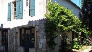 Un edificio de dos plantas con fachada de piedra y contraventanas verdes.