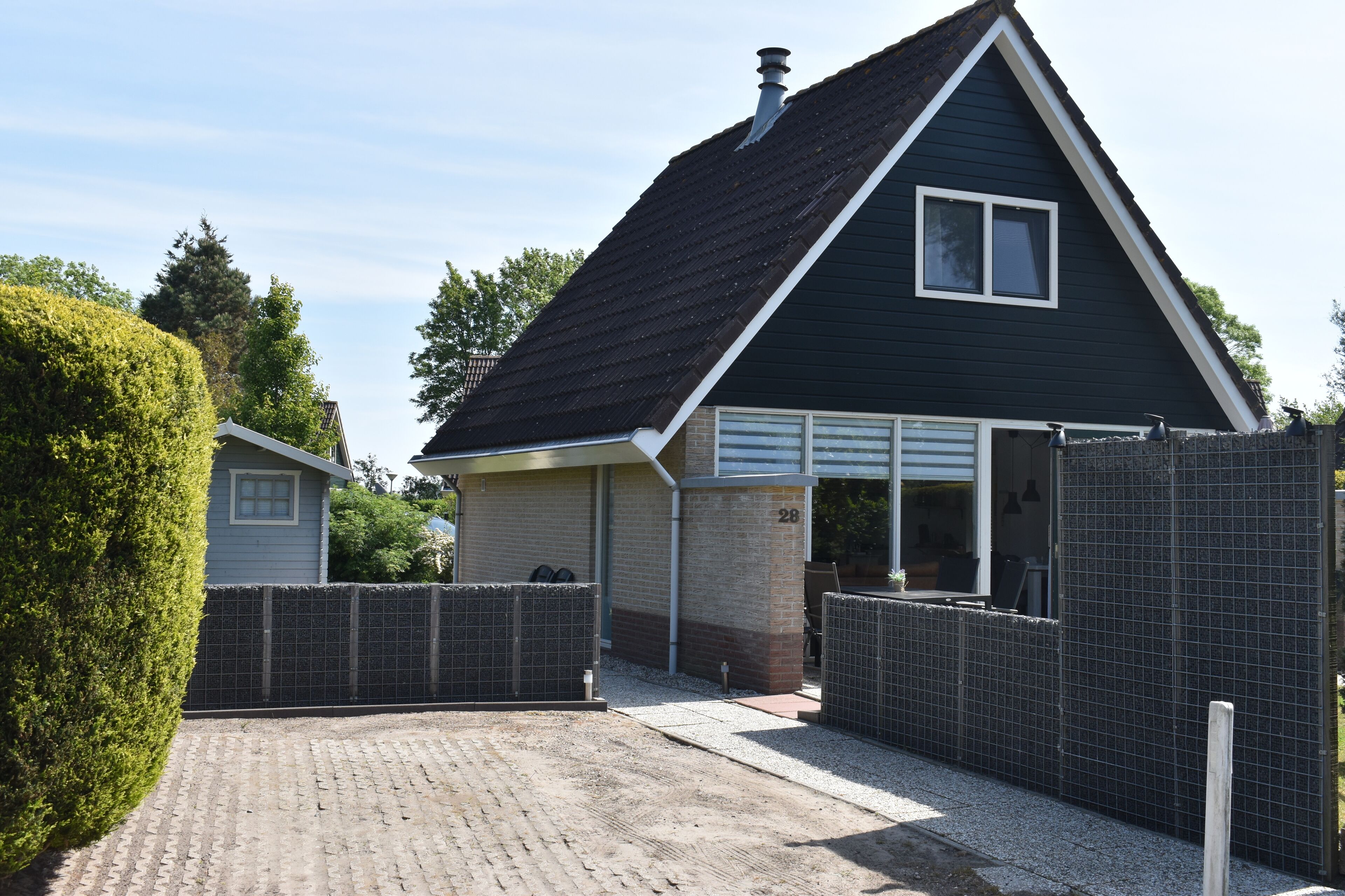 Ein zweistöckiges Haus mit dunklem Dach, der Hausnummer '28' und einem ehrfurchtgebietenden Einfahrtstor.