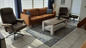 A modern living room with a brown sofa, two armchairs, a coffee table, and patterned rugs. - Comfortable holiday home near the beach with garden, with playground and pool (Sint Maarten)
