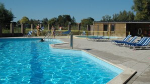 A swimming pool with clear blue water, surrounded by lounge chairs and a fenced area. - Comfortable holiday home near the beach with garden, with playground and pool (Sint Maarten)