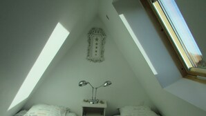 Ein Schlafsaalzimmer mit Oberlicht, einem Bett mit Kissen, einem Nachttisch mit Lampe und einem dekorativen Stern an der Wand.
