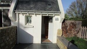 Ein weißes Gebäude mit schwarzem Dach, einem kleinen Fenster und einer Tür, die in den Innenraum führt.