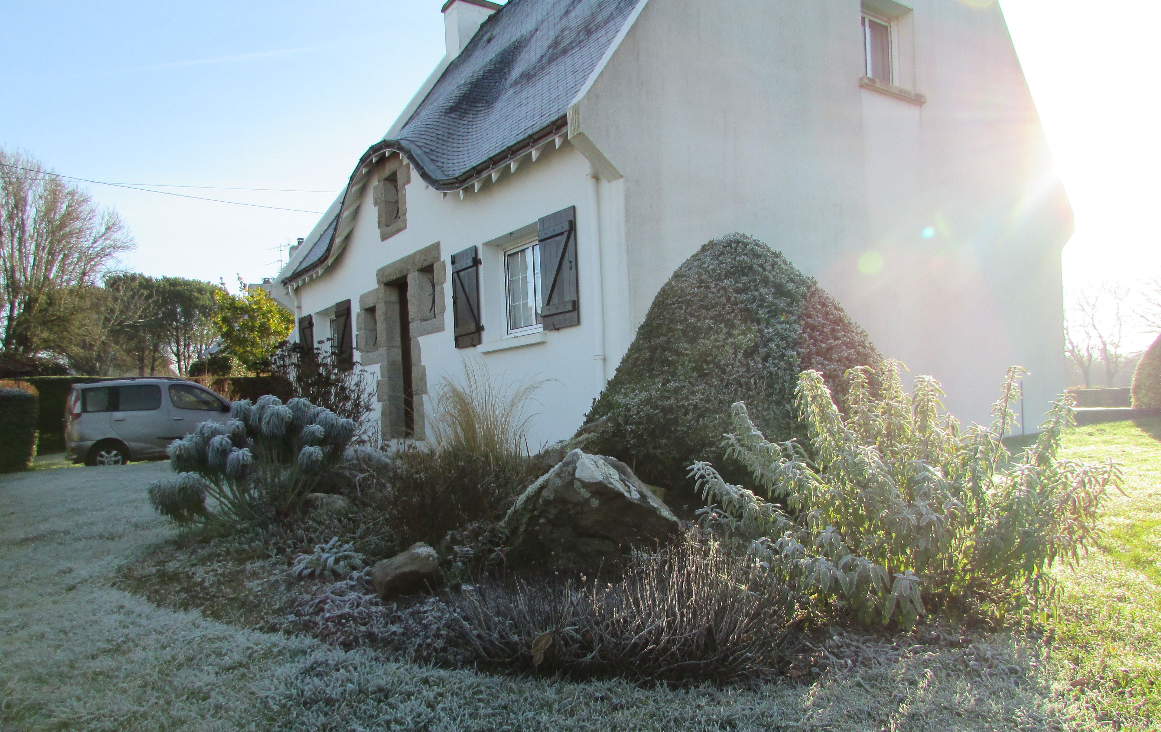 Une maison avec une façade en pierre, un toit en pente et un petit porche à l’avant.