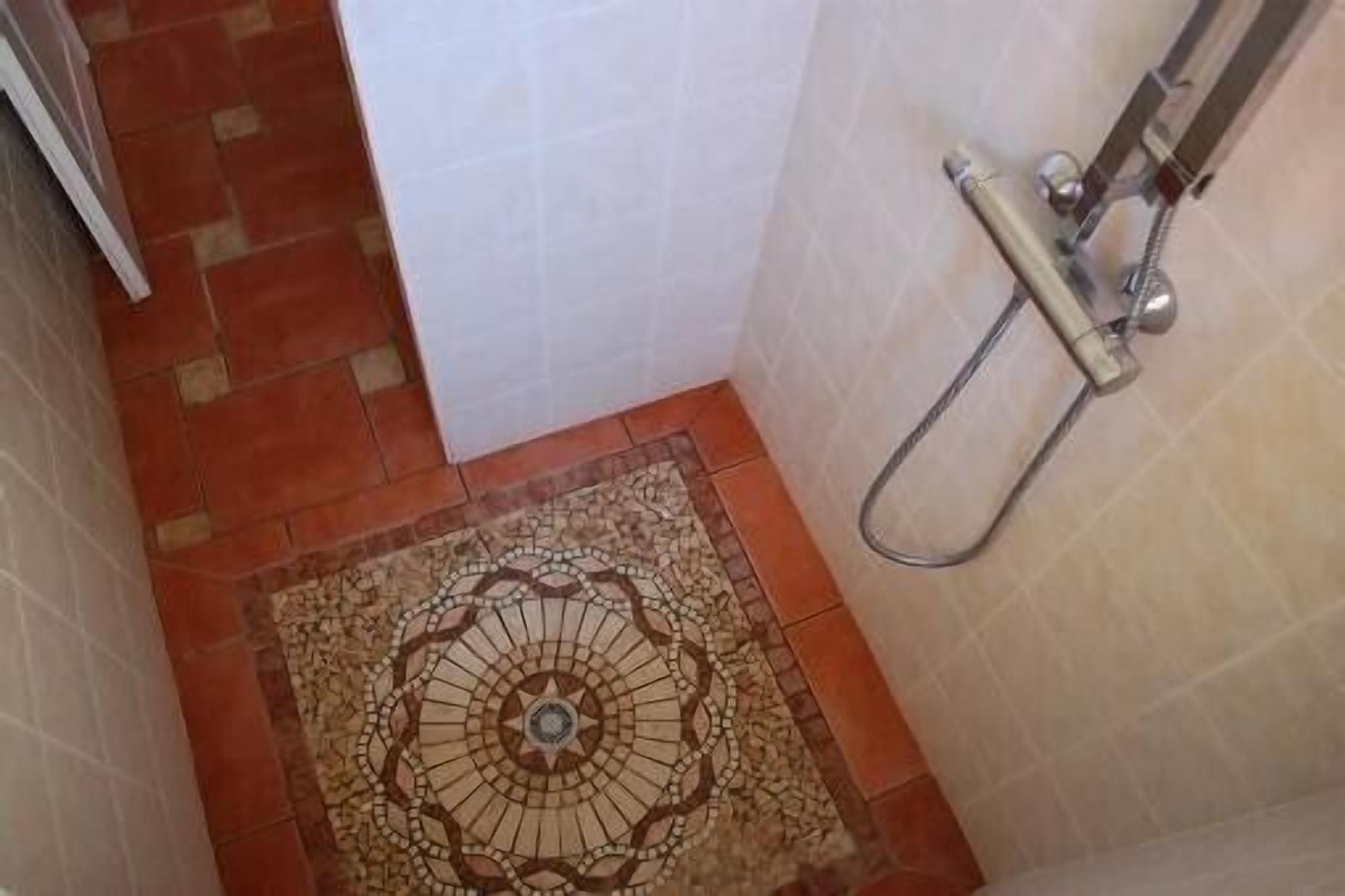 Une salle de bain avec un carrelage décoratif, un espace douche et une porte blanche.