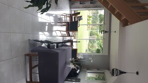 A compact kitchen with a dining area, a window with a view of the garden, and a small sink. - The charm of the countryside to the city (Barentin)