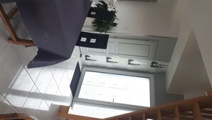 A modern kitchen with a large window, a dining area with a purple tablecloth, and a staircase leading to an upper floor. - The charm of the countryside to the city (Barentin)
