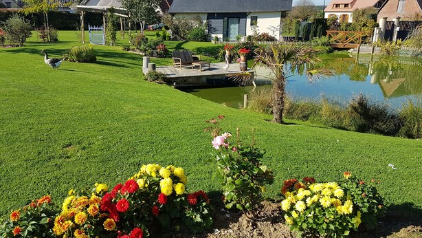 A residential area with a well-maintained lawn, a pond, and colorful flower beds. - The charm of the countryside to the city (Barentin)