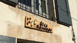 A building with a wooden sign that reads "Cite Randolfo" and a large window with shutters.