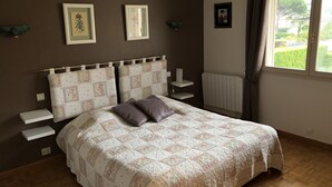 Une chambre avec un grand lit, deux tables de chevet, un radiateur et des tableaux encadrés accrochés au mur.