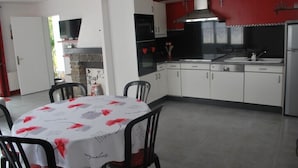 A modern kitchen with white and red cabinetry, a built-in oven, and a dining area with a round table and chairs.