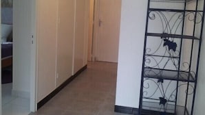 A hallway with a metal rack, a door, and a tiled floor.