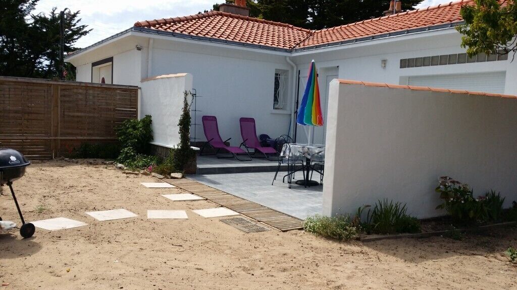 A house with a patio area, a barbecue grill, and two purple lounge chairs.