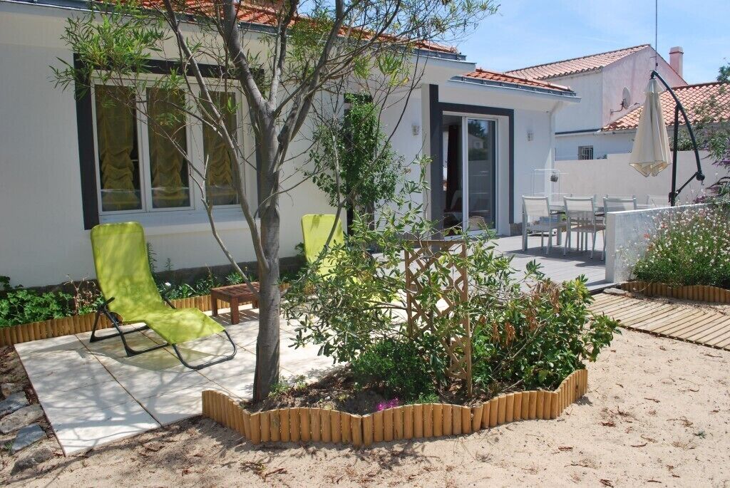 Et moderne hus med en patio, en grøn stol og en lille have.