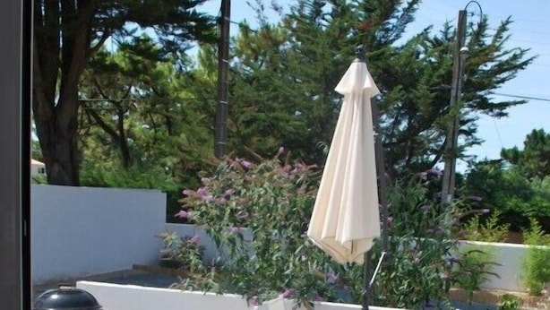 A patio with a table and chairs, an umbrella, and a grill.