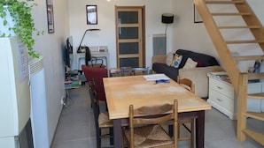 A compact living space with a dining area, a sofa, a staircase, and a radiator.