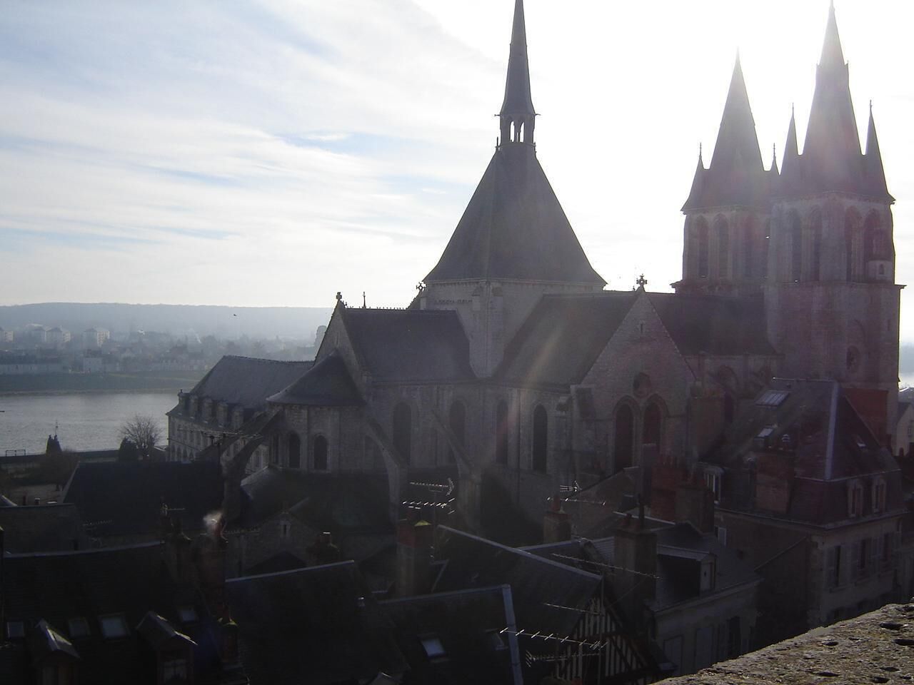 Ein historisches Gebäude mit mehreren Türmen und einem markanten Hauptturm, das auf ein Gewässer blickt.