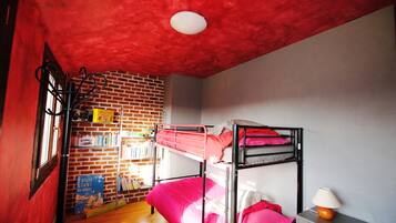 Une chambre avec un lit superposé, une bibliothèque, un bureau avec une lampe et un plafond rouge.