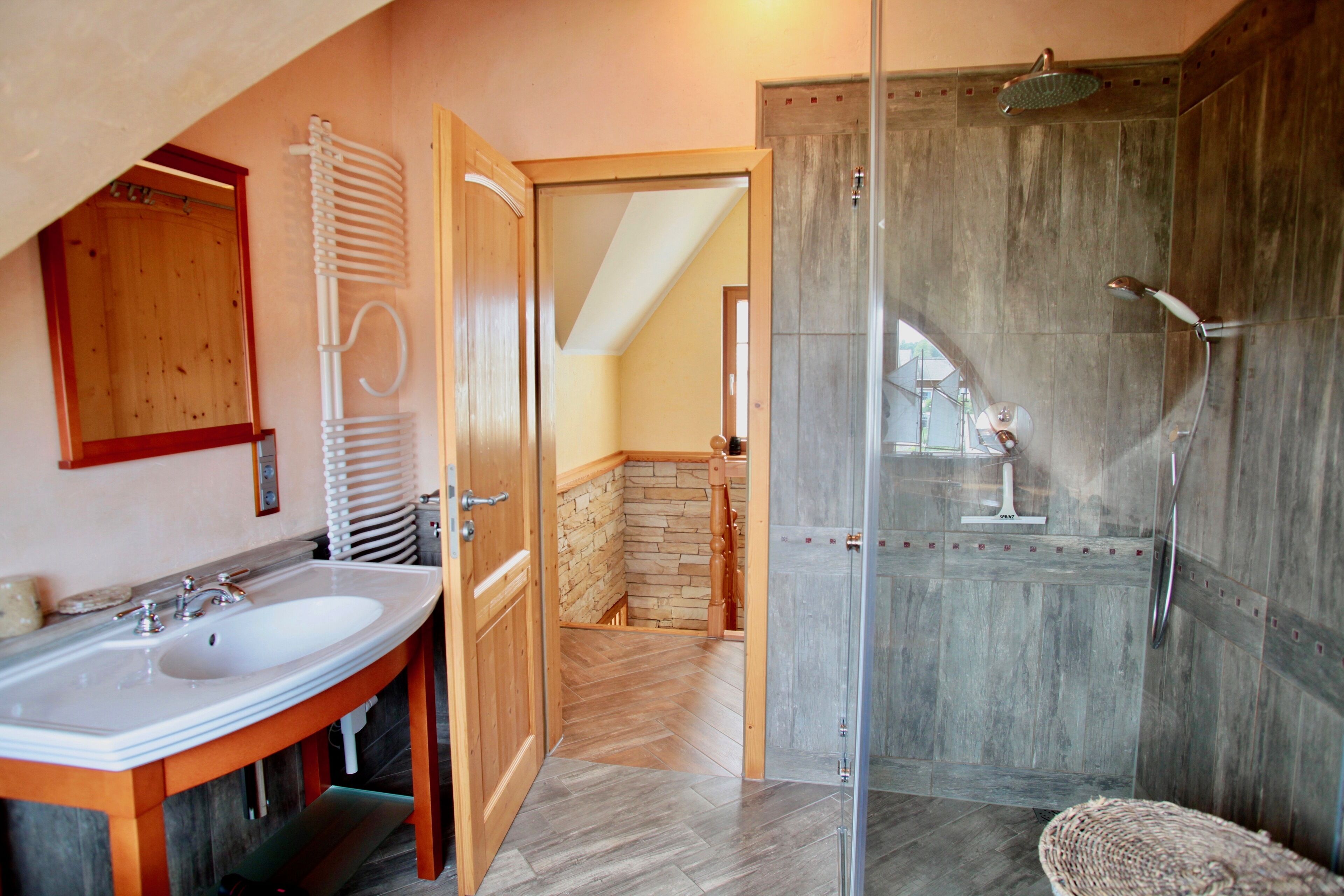 Une salle de bain avec deux lavabos, une douche et un sol carrelé en motif chevron.