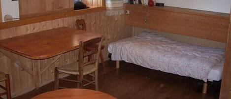 Una habitación de madera con una cama, una mesa y una silla.
