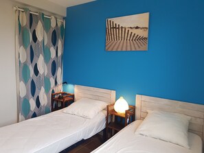 A room with two beds, a blue wall, and a beach-themed painting. - Morgat 150 m from the beach, 6 people, 3 bedrooms, 100m², renovated (Crozon)